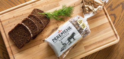 A top view of sliced rye bread with dill on a wooden tray, perfect for food photography.