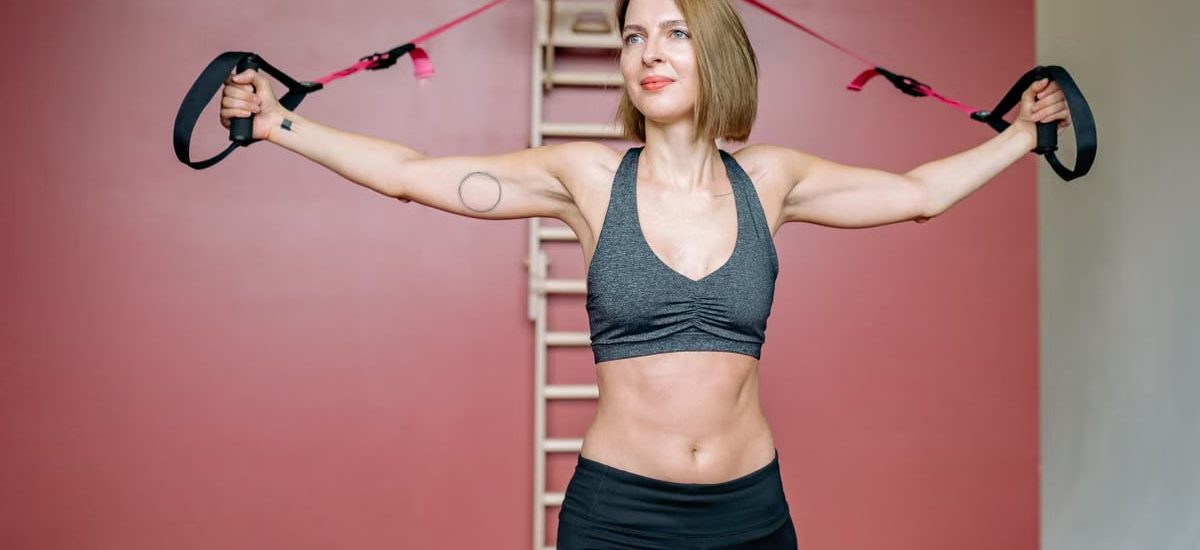 Fit woman in activewear using resistance bands for home workout.